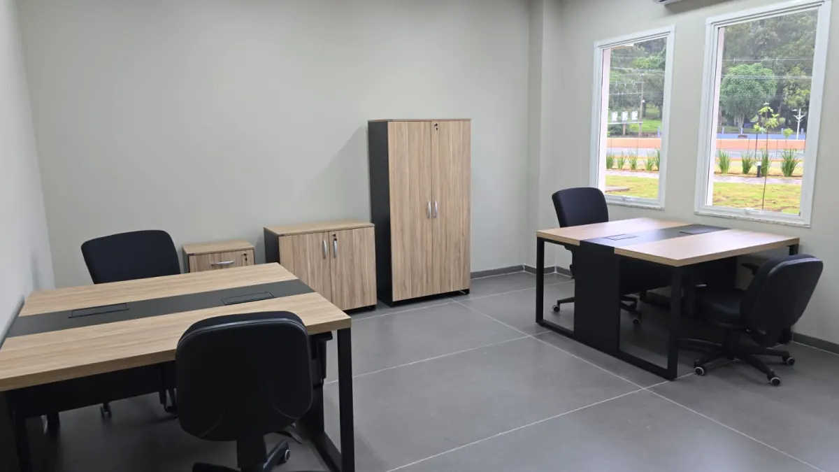 Sala administrativa com estações de trabalho, cadeiras giratórias e armários