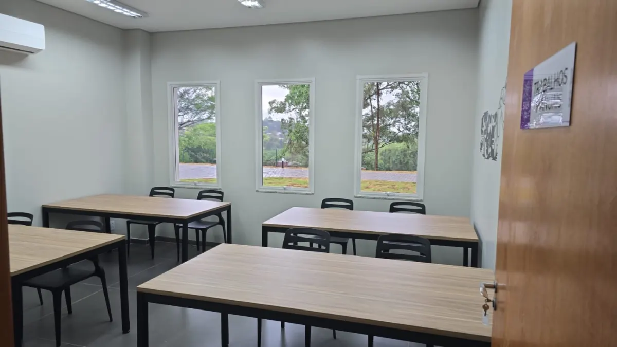 Sala de treinamento com mesas retangulares e cadeiras fixas